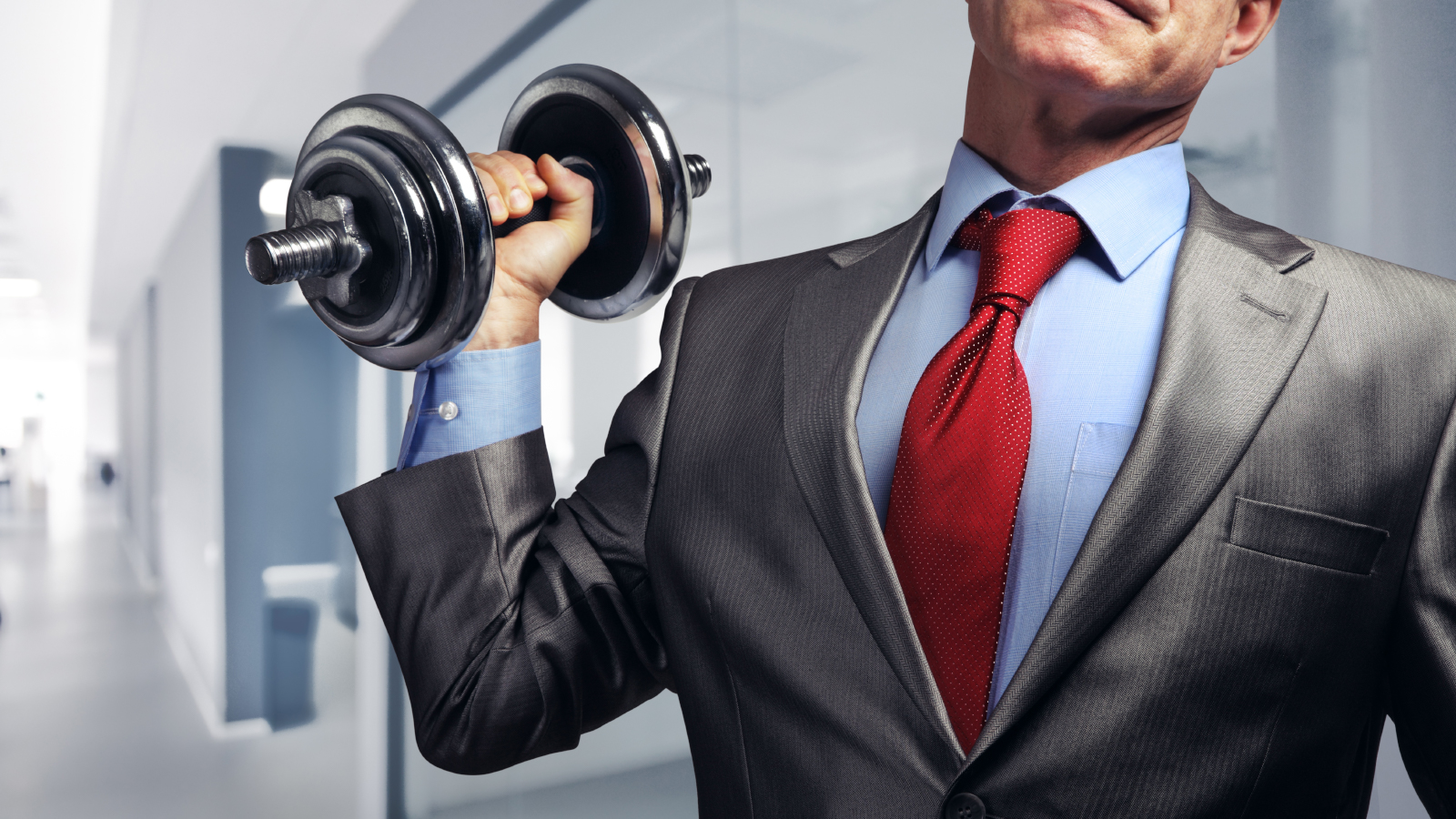 Man in suit lifting dumbbell.